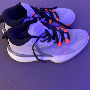 Nike sneakers med orange detaljer - Snygga jordens sneakers i grå med svarta och orange detaljer. Skorna har en modern design med snörning och en bekväm sula. Perfekta för en sportig look.