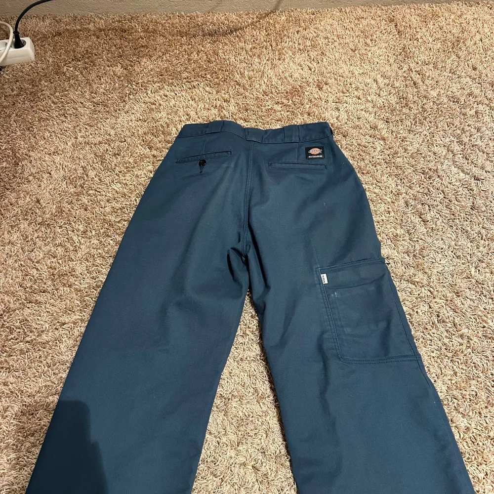 Säljer ett par blå arbetsbyxor från Dickies Skateboarding-kollektion. Byxorna har en loose passform och är tillverkade i slitstarkt material med flex för extra komfort. De har flera praktiska fickor och en diskret logga på benet.. Farkut & Housut.