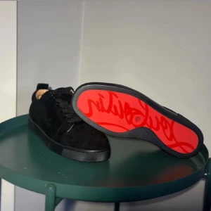 Svarta sneakers med röd sula - Snygga svarta sneakers med en iögonfallande röd sula. Skorna har en klassisk design med snörning och är perfekta för en stilren look.Det är äkta loubs!!