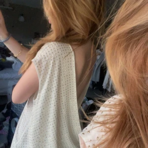 Vit glittrig omlottopp från Michael Kors - Säljer en elegant vit omlottopp från Michael Kors med glittriga detaljer. Toppen har en djup v-ringning och är ärmlös, vilket ger en stilren look. Perfekt för att lysa upp vilken outfit som helst! ✨