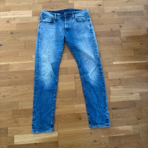 Blå jeans från G-Star RAW - Säljer ett par snygga blå jeans från G-Star RAW, modell 3301. De har en klassisk femficksdesign och en dragkedja. Perfekta för en avslappnad stil med en slim passform.