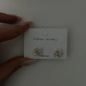 Örhängen med kristalldetaljer  - Snygga glittriga örhängen från Fashion Jewelry med S925 post. Perfekta för att ge en touch av glamour till din outfit. De är små och eleganta, vilket gör dem lätta att bära hela dagen. Aldrig använda! Sista bilden visar att dom fortfarande är plomberade🩷