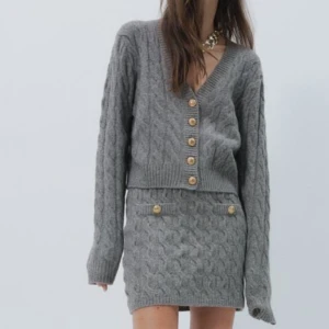 Grå stickad kofta från H&M - Säljer en snygg grå stickad kofta från H&M med kabelstickat mönster och dekorativa guldknappar. Koftan har en v-ringad design och långa armar. Nypris ca 250. Aldrig använd bara testad. Priset är diskuterbart. 