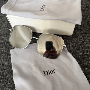  solglasögon från Dior - Snygga solglasögon från Dior med spegelglas , . Bågarna är i silver och kommer med ett  fodral putsduk och kort.   Köparen betalar med Swish 