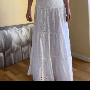 Vit långkjol från Salsa Jeans - Säljer en vacker vit långkjol från Salsa Jeans med broderade detaljer. Kjolen har en luftig passform och är perfekt för sommarens varma dagar. Den är tillverkad i ett lätt och bekvämt material med ett fint mönster av broderade blommor. Aldrig använd, Nypris 800kr