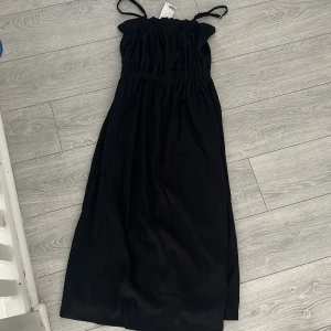 Svart klänning från H&M - Snygg svart klänning från H&M med smala axelband och elastisk överdel. Perfekt för en stilren look. 