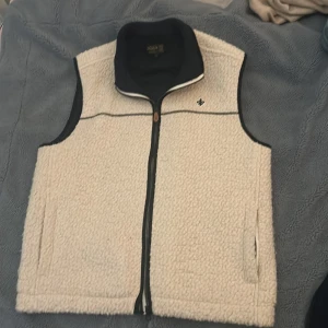 Morris fleeceväst - Väst från Morris som inte säljs längre i helt nytt skick 10/10. Den är i princip oanvänd då jag inte passas med vit färg. Nypris 1500kr. Storlek large, sitter bra på dig som är +185cm och väger från 75kg uppåt.