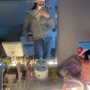 Grå hoodie med dragkedja - Säljer en bekväm grå hoodie med dragkedja och fickor framtill. Perfekt för en avslappnad stil. Den har en huva och långa ärmar, vilket gör den idealisk för kyligare dagar.