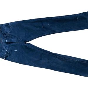 Svarta jeans från Nudie Jeans - Snygga mörkblå jeans från Nudie Jeans med en slim passform. De har en klassisk femficksdesign och subtila slitningar för en trendig look. Perfekta för en stilren vardagsoutfit.