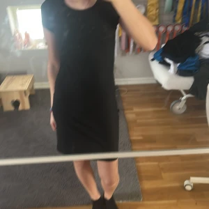 Svart klänning från RYMLS - Snygg svart klänning från RYMLS med en tight passform. Klänningen har korta ärmar och är perfekt för en stilren look. Den är tillverkad i ett mjukt och bekvämt material som formar sig fint efter kroppen.