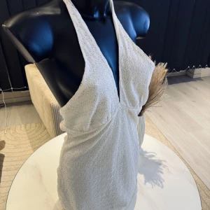 Vit halterneck klänning - Elegant vit halterneck klänning med ett subtilt vågigt mönster. Klänningen har en djup v-ringning och är perfekt för somriga tillfällen. Materialet är mjukt och följsamt, vilket ger en smickrande passform. Passar perfekt i M/L storlek. Jag rekommenderar den varmt.🌸👌