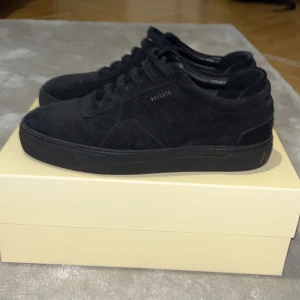 Svarta sneakers från Axel Arigato - Snygga svarta sneakers från Axel Arigato i mocka. Skorna har en stilren design med snörning och rund tå. Perfekta för en trendig look. Knappt använda. Pris kan diskuteras. står ej för frakt, kan mötas upp i GBG