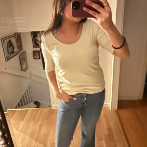 Beige ribbad topp - Säljer en beige ribbad topp med trekvartsärm. Toppen har en rund halsringning och är gjord i ett mjukt material. Tröjan är från Vera Moda i storlek M