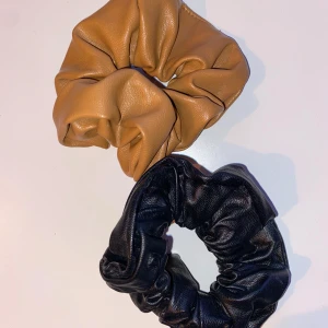 Hårsnoddar i skinnimitation - Två snygga hårsnoddar i skinnimitation, en i svart och en i beige. Perfekta för att ge din frisyr en trendig touch.