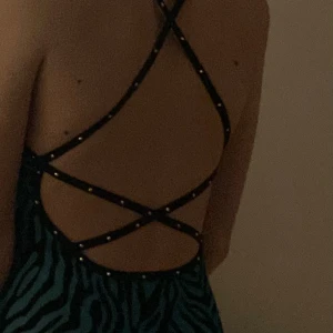 Turkos Rygglös konståkningsklänning - Turkos/zebra konståkningsklänning med öppen rygg & kristaller, från sagester. Helt ny aldrig använd. Säljs då den inte blivit använd och är för liten. Inga defekter. passar för cirka 10-12 år eller yngre