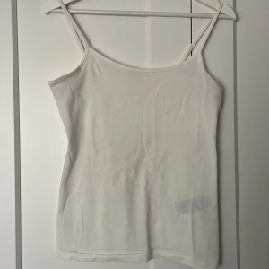 Vit linnetopp från JDY - Säljer en enkel och stilren vit linnetopp från JDY. Toppen har smala axelband och är perfekt för varma dagar. Passar bra att ha under en tröja eller som den är.