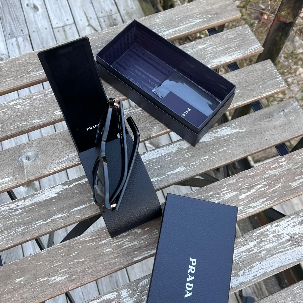 Snygga svarta solglasögon från Prada med rundad form och mörka linser. De har en stilren design med subtila detaljer på bågarna. Perfekta för att ge en touch av lyx till din stil. Nypris 5500 kr. Allt og tillkommer. Asusteet.