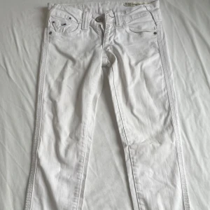 Vita jeansbyxor - Snygga vita jeansbyxor med normal passform och klassisk design. Byxorna har fem fickor och en knappgylf. Perfekta för en stilren look.