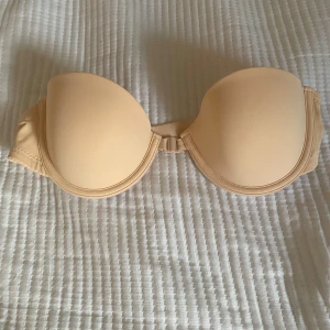 Beige/nude axelbandslös bh - Säljer en beige/aprikos/nude axelbandslös bh🫶Perfekt för att bära under axelbandslösa toppar och klänningar. Säljer pga att kuporna var för lite för små för mig som har B, så skulle säga att dem är en A-kupa. Står som storlek XS. Går att justera storlek i ryggen. Helt oanvänd och i nyskick, endast provad. Det är bara att skriva om ni har frågor eller vill ha fler bilder🥰 