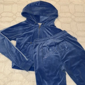 Blå sätt från Juicy Couture - Säljer ett blåt sätt från Juicy Couture tröjan är xs byxorna är xxs med dragkedja och huva. Sättet har långa ärmar/ben med en ljusblå rand längs sidorna och texten 'Juicy' i glittriga stenar på ryggen. Perfekt för en avslappnad och stilren look.
