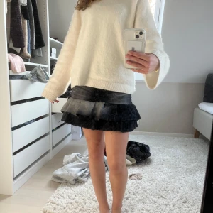 Svart jeanskjol med volang - Trendig svart jeanskjol med volangdetaljer. Kjolen har en kort längd och en cool ombre-effekt från mörkgrått till svart. Perfekt för att ge din outfit en edgy touch. 