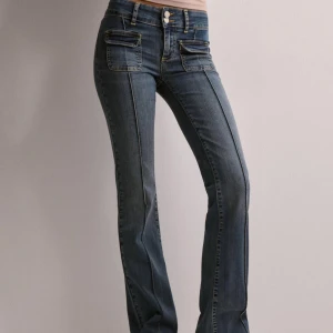Blå bootcut jeans - Snygga blå bootcut jeans med låg midja och klassisk femficksdesign. Perfekta för en avslappnad stil med en touch av retro. De har en knapp och dragkedja framtill.