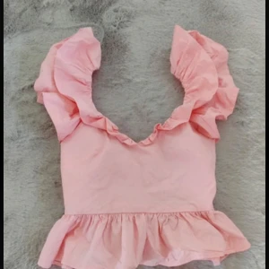 Rosa volangtopp - Söt rosa topp med volanger och knytning i ryggen. Toppen har en croppad design och är perfekt för sommarens varma dagar.