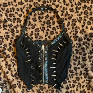Svart korsett med dragkedja och nitar - Säljer en svart korsett från Killstar med coola nitar och dragkedja.