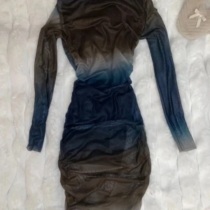 Mörk klänning med ombre-effekt - köpt i Indonesien - Snygg klänning med en cool ombre-effekt i mörka toner. Den har långa ärmar och en tight passform som framhäver figuren. Perfekt för en kväll ute eller en speciell tillställning.