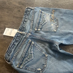 Blå jeans från Replay - Snygga blå lågmidjade jeans från Replay med bootcut-stil och slitna detaljer. Midjemått: ca 35 cm och innerbenslängden: 76 cm. De har lite slitage längst ner men verkligen inget man tänker på. Köpta för ca 750 kr, kom privat för fler bilder.💕