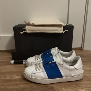 Blåa Valentino opens  - Säljer mina valentino opens i färgen vit/blå, storlek 42!! Skorna har sina defekter, både inne i skon och lite slitningar längst fram på skorna men inget man lägger större fokus på. Alla nitar är kvar!! Skorna är annars väldigt väldigt väldigt snygga och populära, samt att denna färg är väldigt sällsynt och svår att få tag i. Box, påse och extra snören ingår vid köp! Hör av er vid fler frågor eller bilder. Börjar på detta priset men absolut går priset att diskutera. Ha det bäst så länge! ;)
