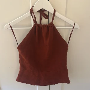  halterneck-topp - Står storlek xs men jag skulle nog säga xs/s! Snygg rostfärgad/vinröd halterneck-topp med knytband i nacken. Perfekt för varma sommardagar eller en kväll ute. Säljer då den var lite för stor! Pris kan diskuteras!