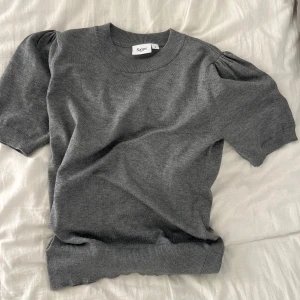 Grå stickad tröja - Säljer en stilren grå tröja från Saint med korta puffärmar och rund hals. Perfekt för en avslappnad look. Tröjan har ribbade kanter vid ärmslut och nederkant. Aldrig använd, pris kan diskuteras🤗