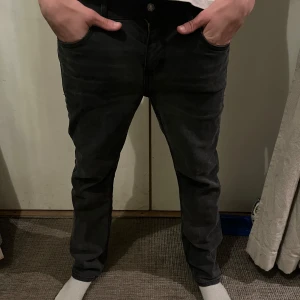  Levi's jeans - Snygga svarta jeans från Levi's med klassisk femficksdesign och knappgylf. Perfekta för en stilren look. Märkeslappen syns tydligt på baksidan.