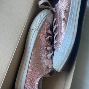 Glittriga rosa sneakers från Converse - Säljer ett par glittriga rosa Converse i storlek 35. Skorna är köpta i Florida. använda ca tre till fem gånger