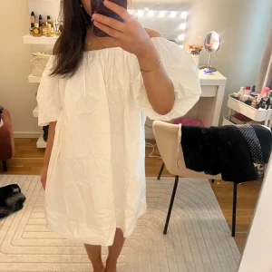 Vit offshoulder klänning - Säljer en söt vit offshoulder klänning med puffiga ärmar. Perfekt för varma dagar och ger en luftig och bekväm känsla. Klänningen har en avslappnad passform och är lätt att styla med olika accessoarer.
