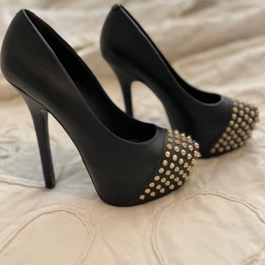 Svarta pumps med nitar - Snygga svarta pumps från Steve Madden med spetsig tå och klack. Skorna har coola nitar framtill som ger en edgy look. Perfekta för att ge din outfit en extra touch av stil.