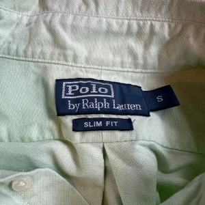 Ljusgrön skjorta från Polo Ralph Lauren - Snygg ljusgrön skjorta från Polo Ralph Lauren i slim fit. Skjortan har långa ärmar och knappar framtill. Den är broderad med den klassiska logotypen på bröstet. Perfekt för en stilren look!