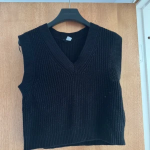 Svart stickad väst - Snygg svart stickad väst med v-ringning. Perfekt för lager-på-lager och ger en stilren look. Passar bra till både skjorta, t-shirt eller bara så 