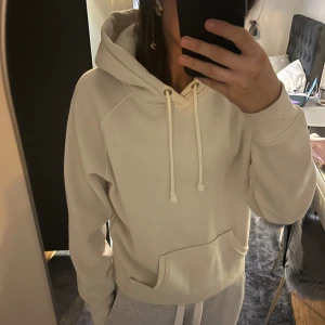 Vit hoodie från Bikbok - Säljer en stilren vit hoodie med dragsko och känguruficka. Perfekt för en avslappnad look. Den har långa ärmar och en bekväm passform.