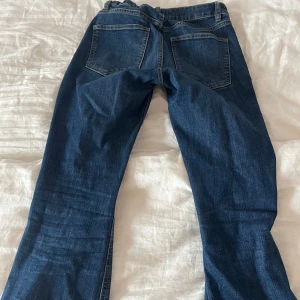 Mörkblå lågmidjade jeans från Lindex - Snygga blå jeansbyxor från Lindex med klassisk femficksdesign och dragkedja. Perfekta för en avslappnad stil. Storlek 170