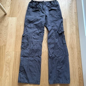 Cargobyxor från Brandy Melville - Snygga grå cargobyxor från Brandy Melville med flera praktiska fickor och en loose passform. Perfekta för en avslappnad stil. Byxorna har en elastisk midja för extra komfort. Passar S och XS 💖💖använt en gång