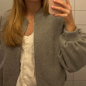 Grå bomberjacka Zara - Säljer en stilren grå bomberjacka med dragkedja. Jackan har långa ärmar med ribbade muddar och en mjuk, bekväm passform. Perfekt för våren! 💝💝