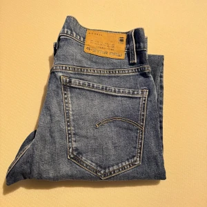 Blå jeans från G-Star RAW - Säljer ett par klassiska blå jeans från G-Star RAW, modell Mosa Straight. De har en rak passform. Perfekta för en avslappnad stil. Knappast använda då de är för små för mig. Storlek ser man på andra bilden. 