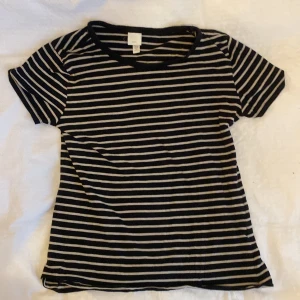 Svartvit randig t-shirt från H&M - En klassisk svart t-shirt med vita horisontella ränder från H&M Basics. T-shirten har rund halsringning och korta ärmar. Perfekt för en mer basic look🫶