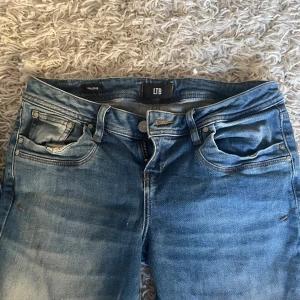 Blå jeans från LTB - Säljer ett par klassiska bootcut blå jeans från LTB med normal passform och låg midja. Jeansen har fyra fickor, dragkedja och knapp framtill  samt snygga slitningar för en avslappnad look. W29 L34