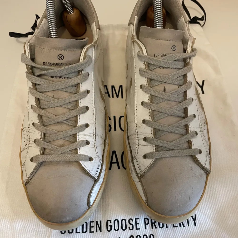 Säljer ett par vita sneakers från Golden Goose med grå detaljer och beige sula. Perfekta för dig som gillar unika detaljer. Sulorna är i bra skick förutom att dem börjar bli lite slitna i hälarna. Riktigt fint skick, nypris: runt 6000 mitt pris 1500! . Kengät.