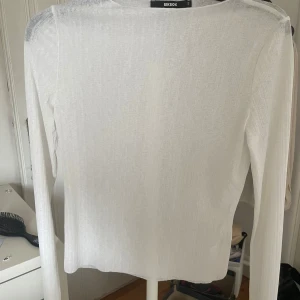 Vit ribbad långärmad topp från BikBok - Säljer en tunn och ribbad vit långärmad topp från BikBok i storlek S. Perfekt att styla lager på lager eller bära som den är. Enkel och stilren design med rund halsringning.