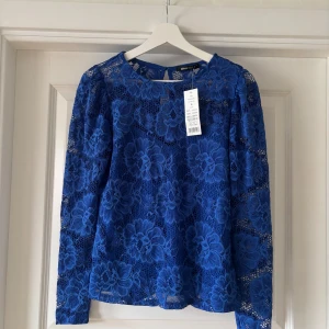 Blå spetsblus från Gina Tricot - Säljer en snygg blå spetsblus från Gina Tricot. Den har en knapp i nacken för enkel påklädning. Helt oanvänd.