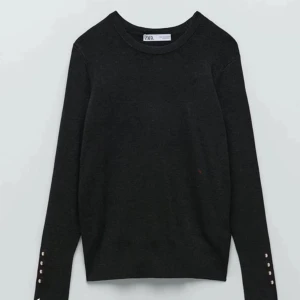 Svart finstickad tröja från Zara med guld knappar - Snygg svart tröja från Zara som inte längre säljs, tröjan har långa ärmar och guldiga knappar längs ärmsluten. Perfekt för en stilren look. Tröjan är väldigt bekväm! Kom privat för egna bilder💝